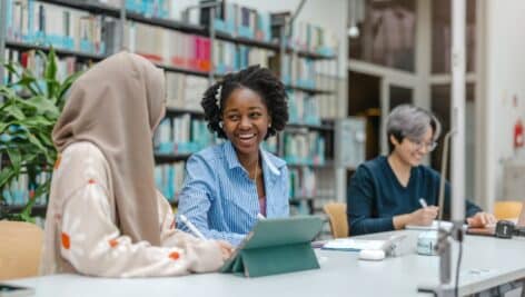 Multiethnic group of students sitting in a library and studying together.