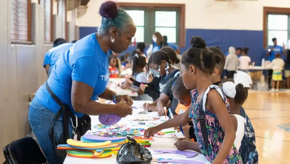 adult helps children with arts and crafts
