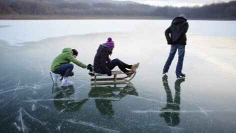 Teenagers having fun sliding on the thin ice