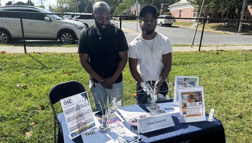 David Day with a Work Enclave student behind a table with educational materials.