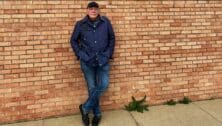 James Patterson standing against a brick wall outside.