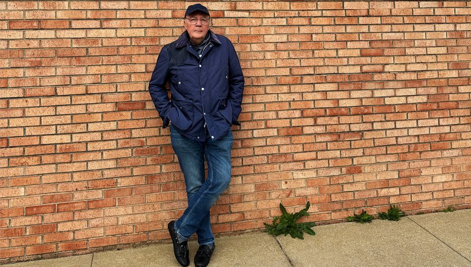 James Patterson standing against a brick wall outside.