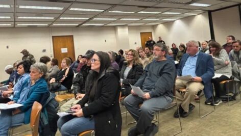 Group of people sit in council room.