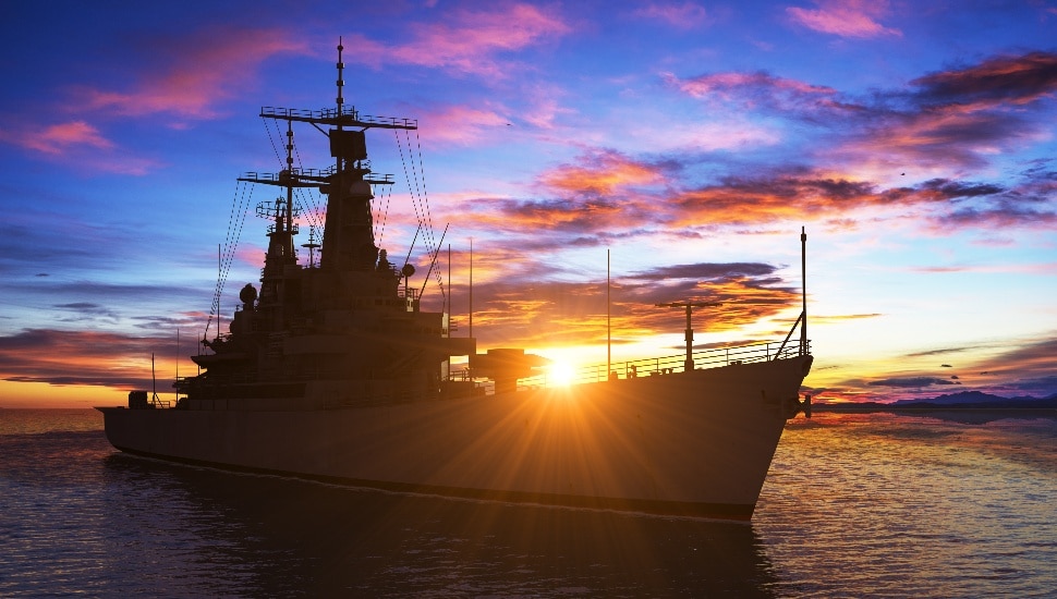 Modern warship in background of sunset.