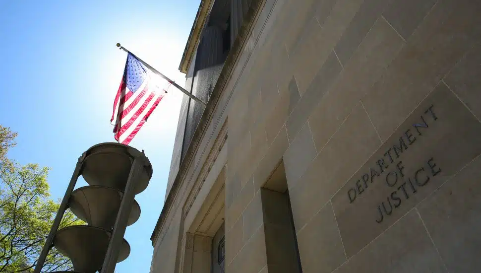 American flag hanging outside Justice Department on sunny day.