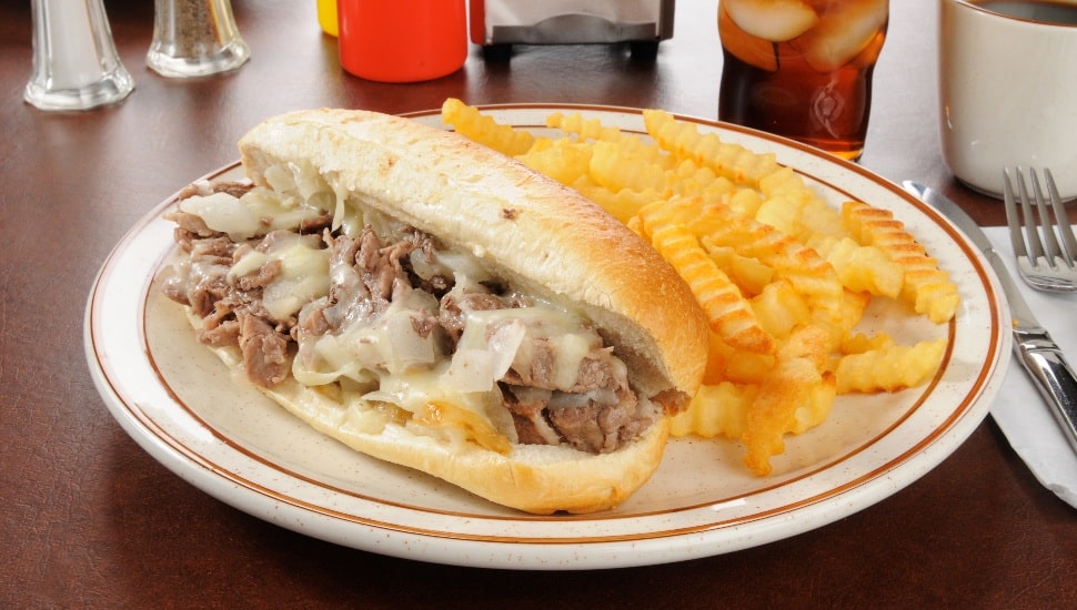Philadelphia Cheesesteak on plate with fries.