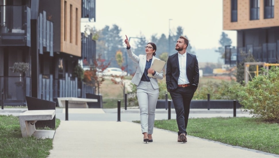 Two business people walk down the sidewalk.