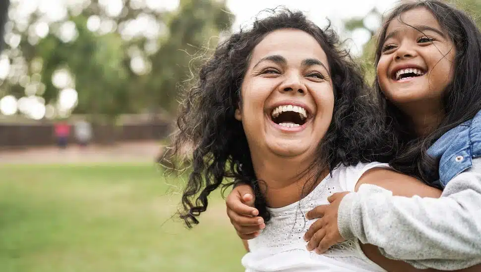 Happy, smiling mother having fun with her daughter outdoors.