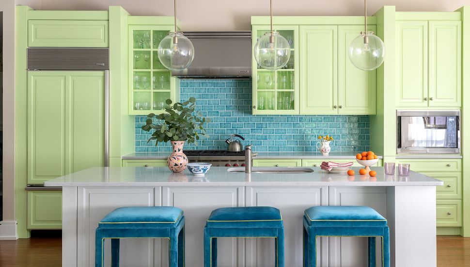 Wayne condo kitchen with green cabinets and blue stools.
