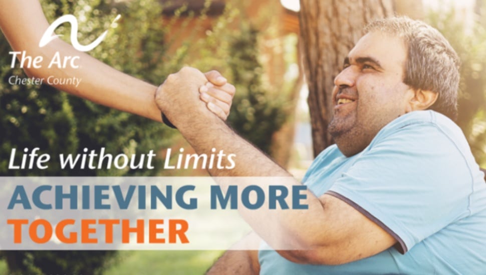 A promotional poster for National Disabilities Awareness Month showing a man in a wheelchair clasping the hand of someone.