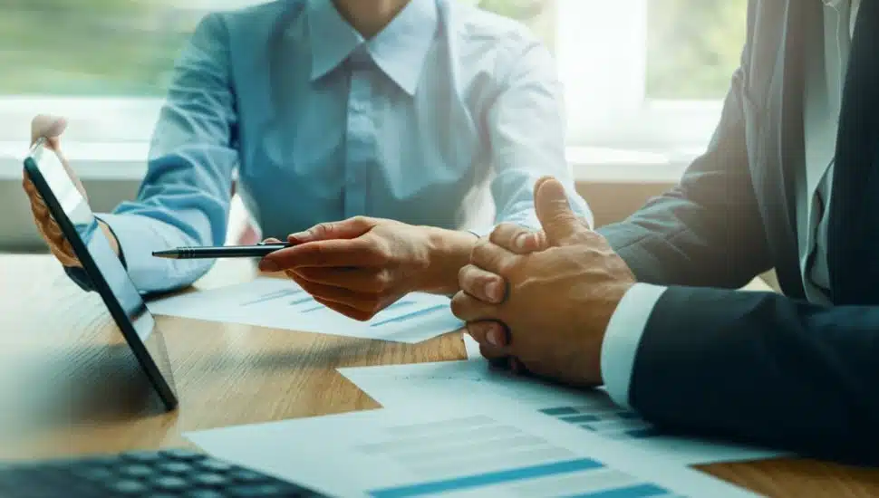 Business consulting services, advisor and businessman working with digital tablet at desk in office.