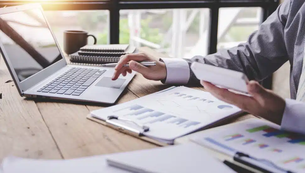 Businessman works at his desk surrounded by paper and computer.