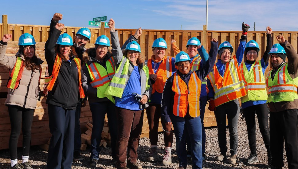 Saint-Gobain workers in group raising a fist with a smile.