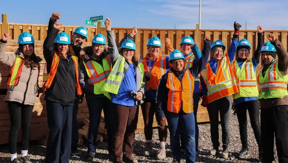 Saint-Gobain workers in group raising a fist with a smile.