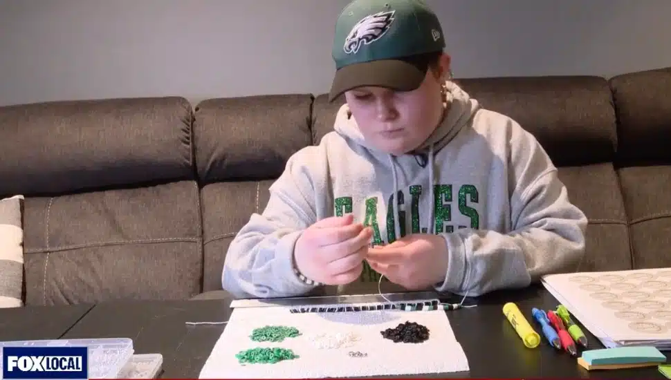 Samantha from Exton wearing Eagles gear and making bracelets.
