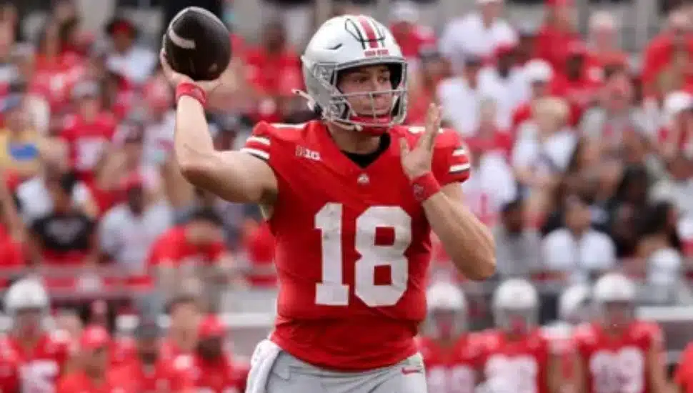 Will Howard throwing a football on field at game.