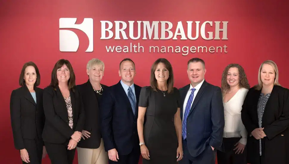 Group photo of financial advisors with firm signage in background.