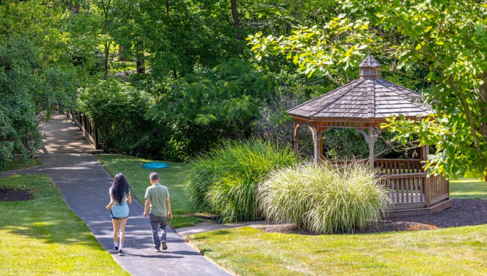 Two people walking by gazebo on Cheserbrook trail.