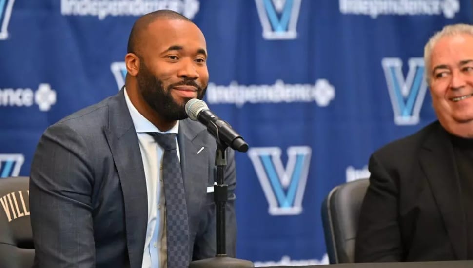 Kyle Neptune sitting a press conference.