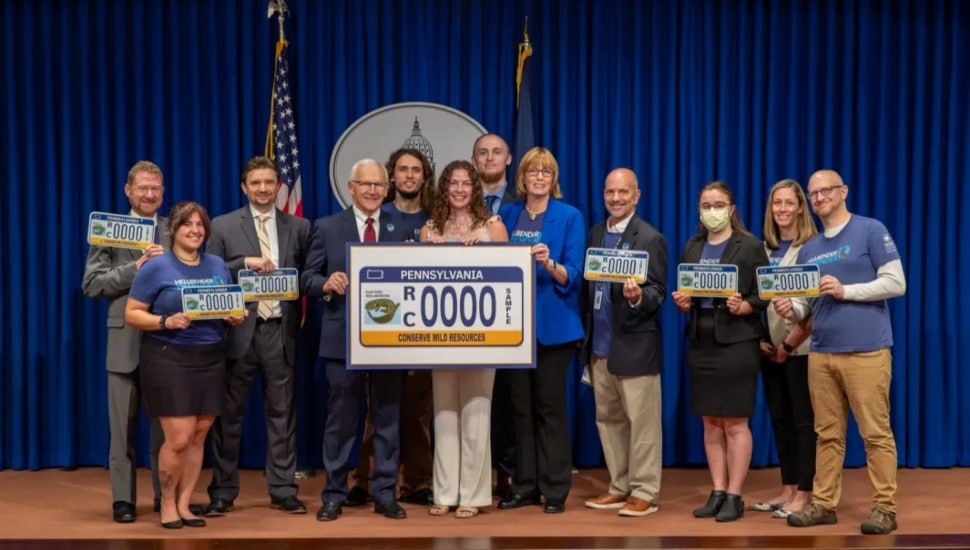 Group of people holding new PA license plate.