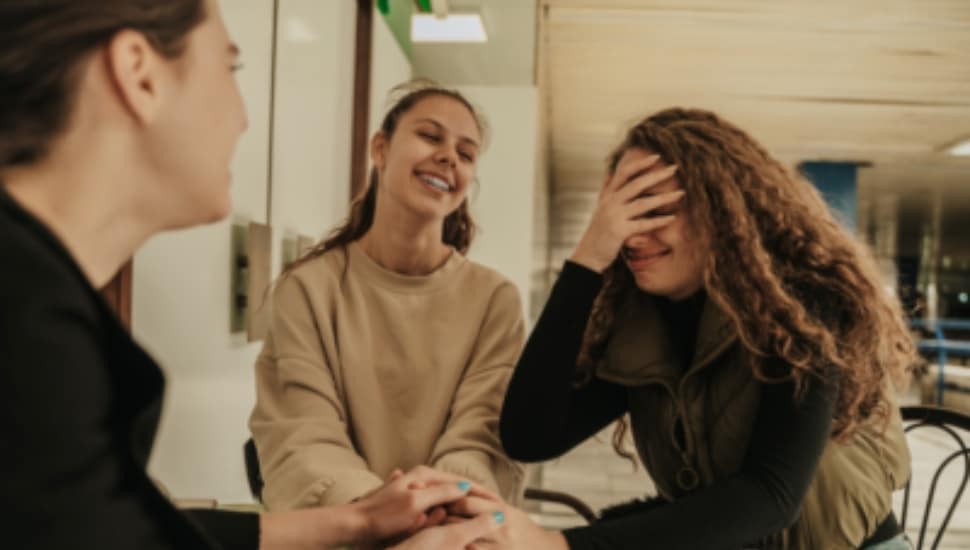 A woman catches herself in an embarrassing moment in front of two people.
