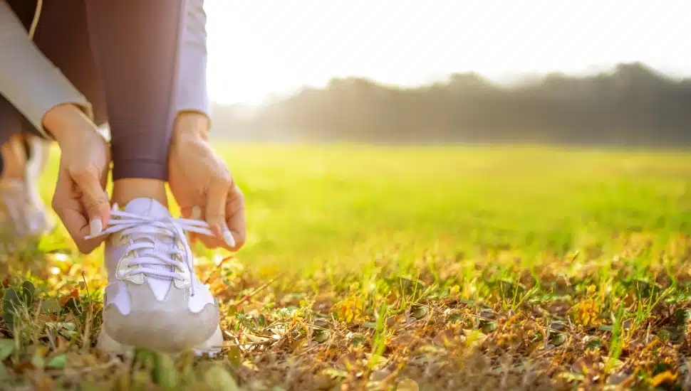 young woman runner tying her shoes preparing for a jog outside at morning.