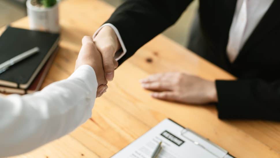 Handshake over image of a blurry resume.