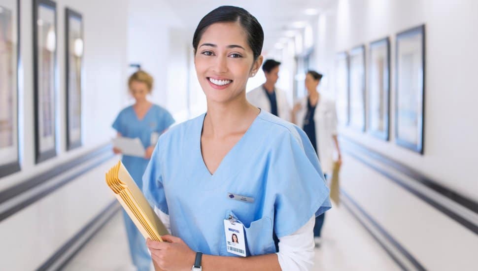 Portrait of smiling nurse in hospital corridor.