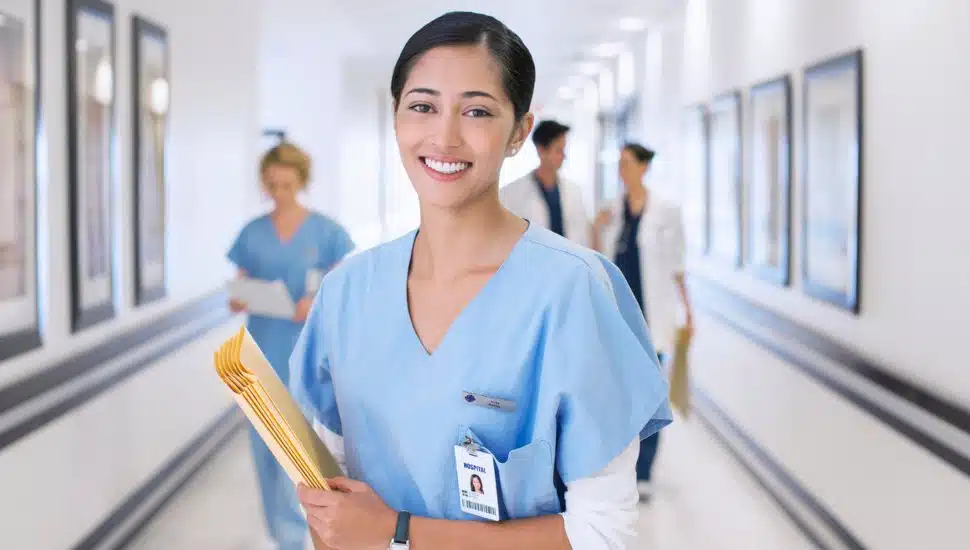 Portrait of smiling nurse in hospital corridor.