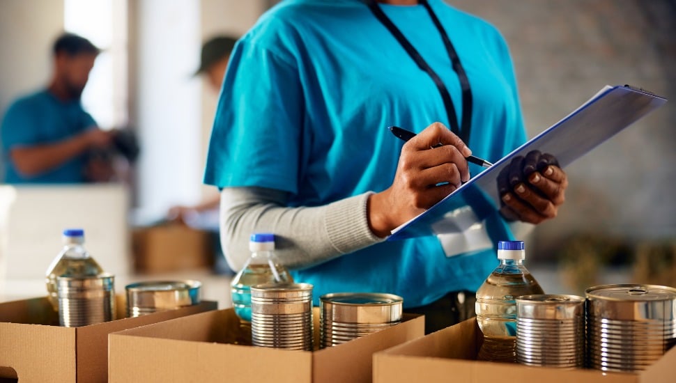 Close up of woman making list of donated groceries while volunteering at food bank.