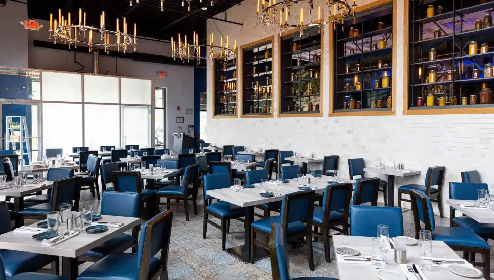 Avola Kitchen & Bar dining room with dark blue chairs and white tables.