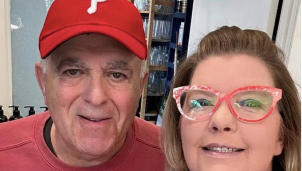 Bill Peters wearing a red shirt and Phillies hat and Cameron Peters wearing light red glasses.