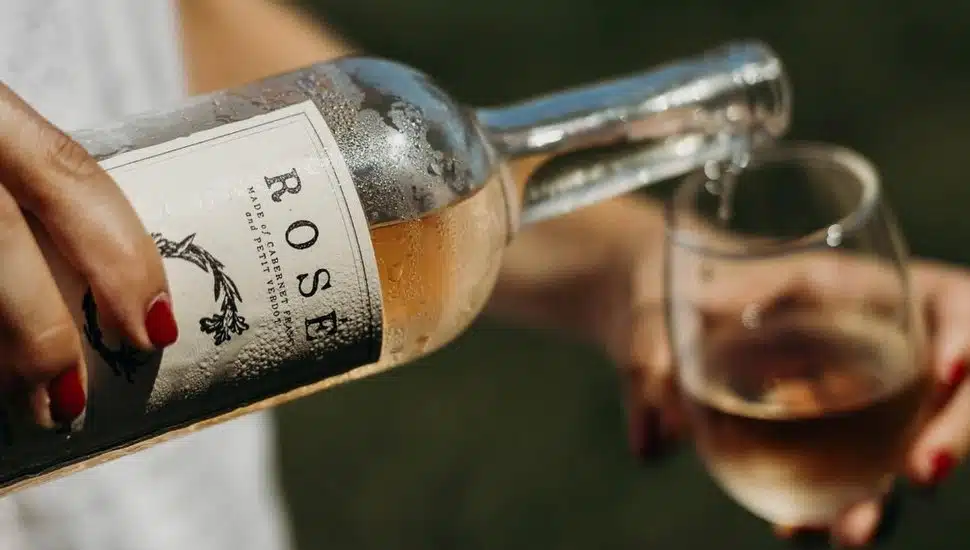 Woman's hand pouring wine into wine glass.