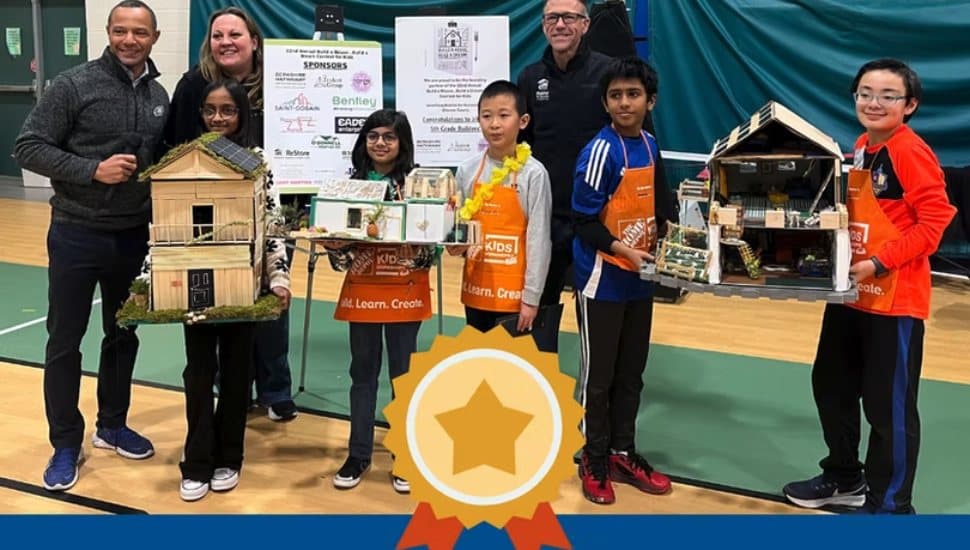 The winners of the contest stand with their model homes facing the camera. First prize was awarded to Agastya Mudigonda and Kevin Ma; second place went to Sanvi Patel; and third place to Jason Kreyling and Dhanvine Vijayabhaskaj. The kids wear Home Depot Aprons and are smiling.