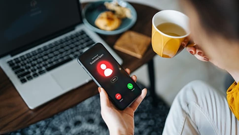Person holding coffee mug sees phone ringing.
