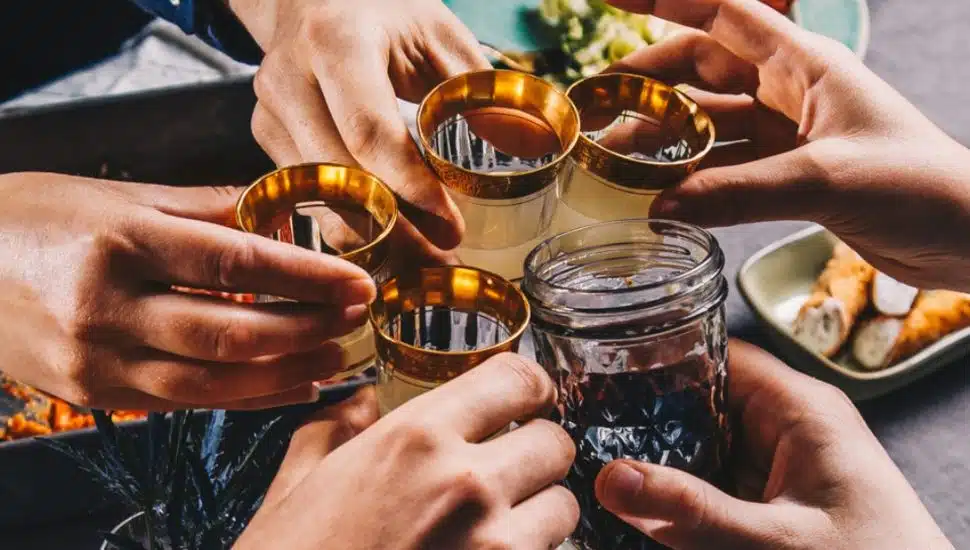 People clinking glasses together to celebrate at dinner table.