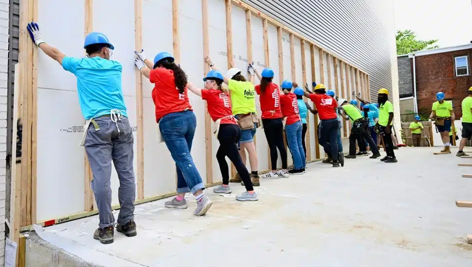 Volunteers raise a wall at a construction site.