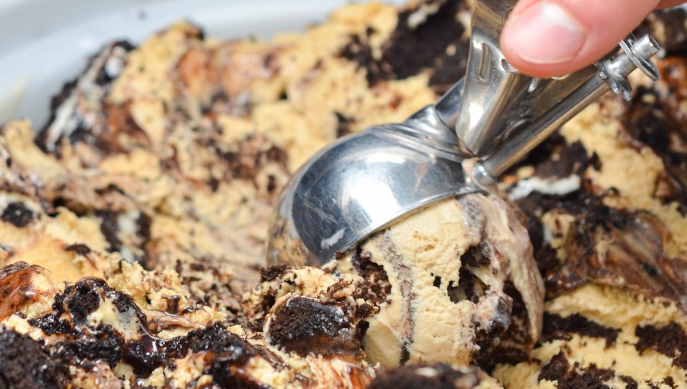 Hand scooping chocolatey ice cream out of container with scooper at Handel's.