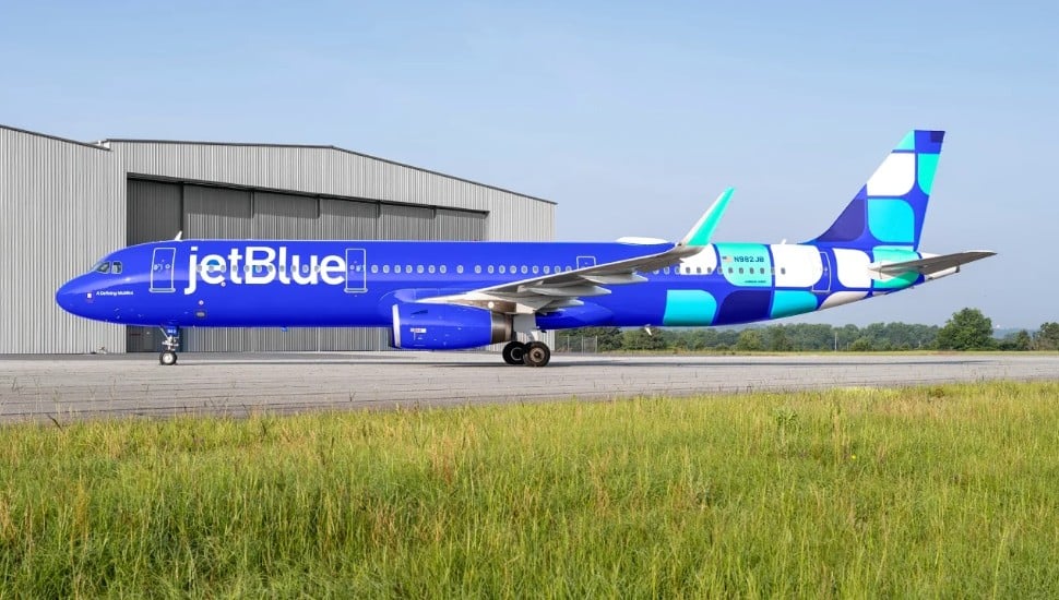 JetBlue plan resting on tarmac, side view.