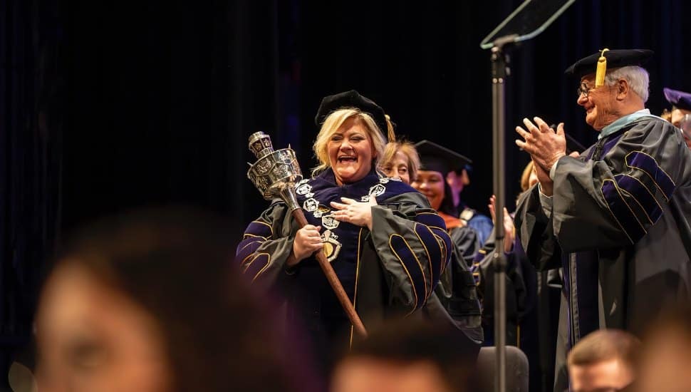 Laurie Bernotsky holding president's scepter next to former WCU president.