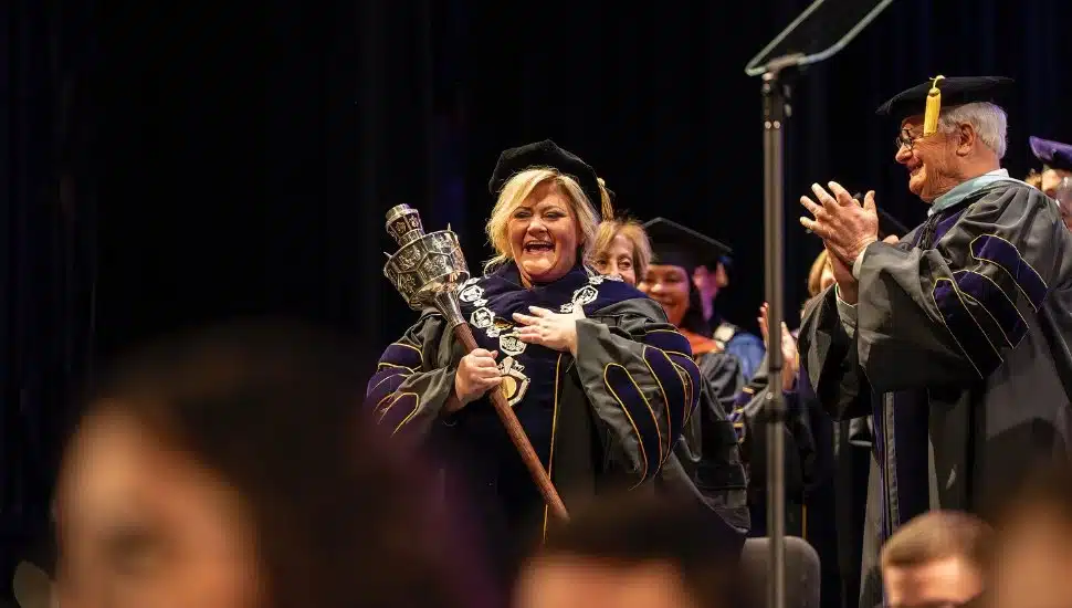 Laurie Bernotsky holding president's scepter next to former WCU president.
