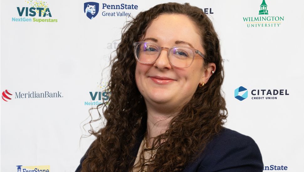 Headshot of Melissa A. Rheinstadter. She wears a black blazer, is turned to the side and is smiling at the camera. She has long dark curly hair and glasses.