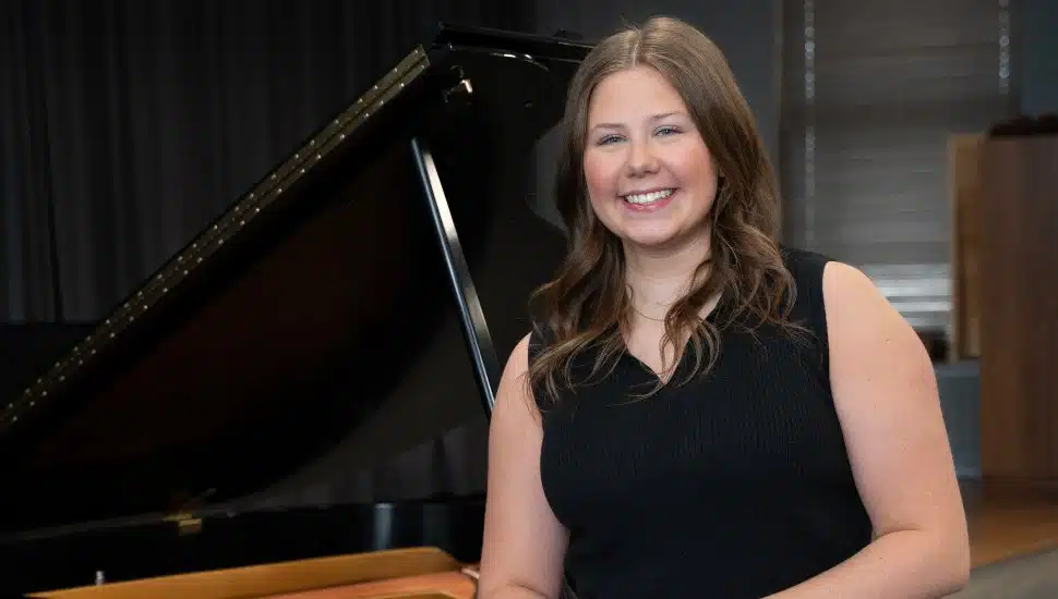 Photo of Olivia Baker with her arm propped on piano.