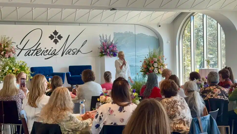 Patricia Nash speaking to audience who sit at round tables.