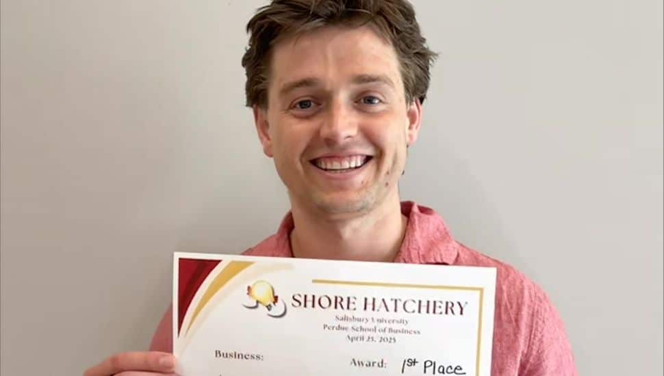Headshot of Jake Henry holding his 1st place award for $35k. He is smiling, has brown hair and a red collared shirt.