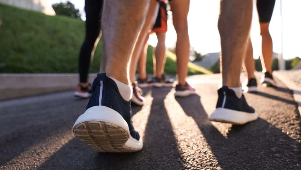 Group of people running outdoors on sunny day, closeup view.
