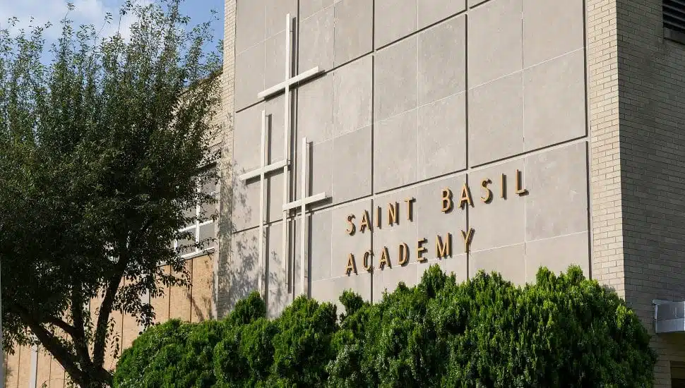 St. Basil's Academy building sign with bushes in front.