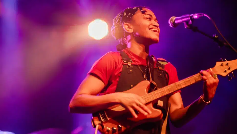 Singer0songwriter, storyteller and producer Sug Daniels performs with guitar in a concert.