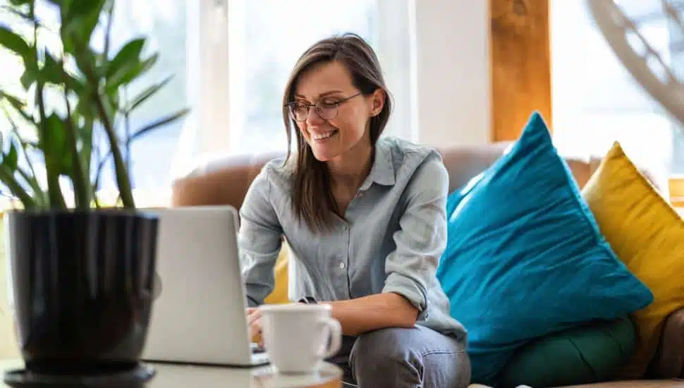 Woman sitting on couch working remote from home.