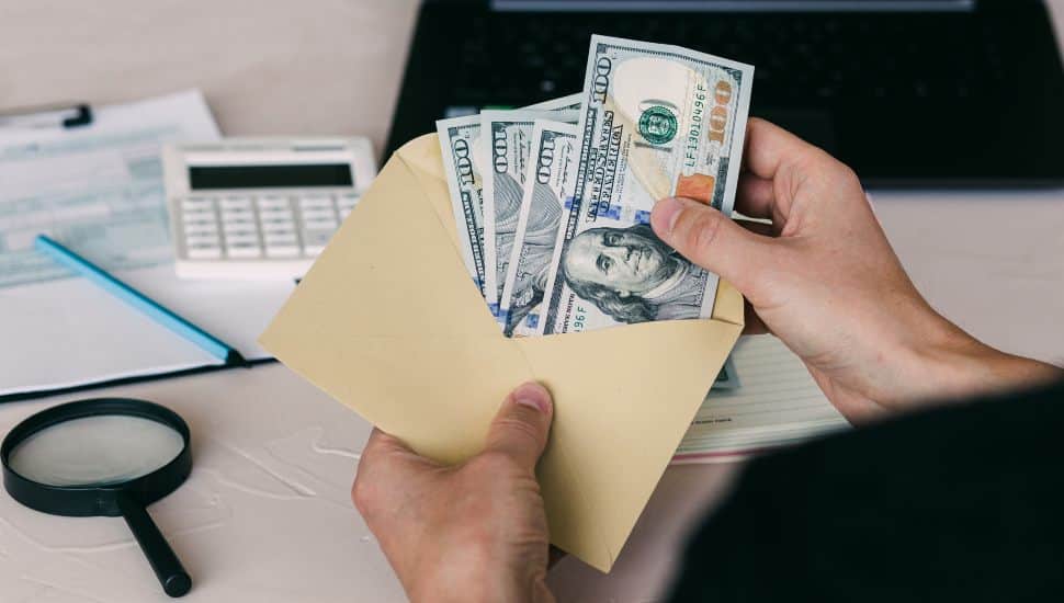 A man's hand holds an envelope with money, counting money American dollars.